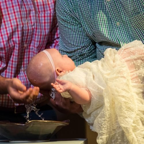 baby girl being baptized by priest in a church